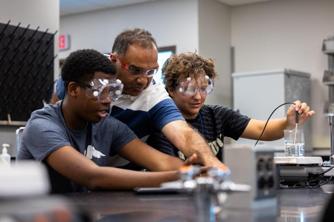 One Kettering professor and two students wear safety glasses while they conduct an experiment.